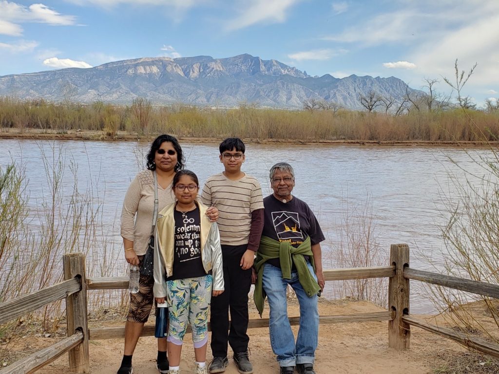 Ravi with his wife Shirley and children Quinn and Priya in front of a lake and mountain landscape