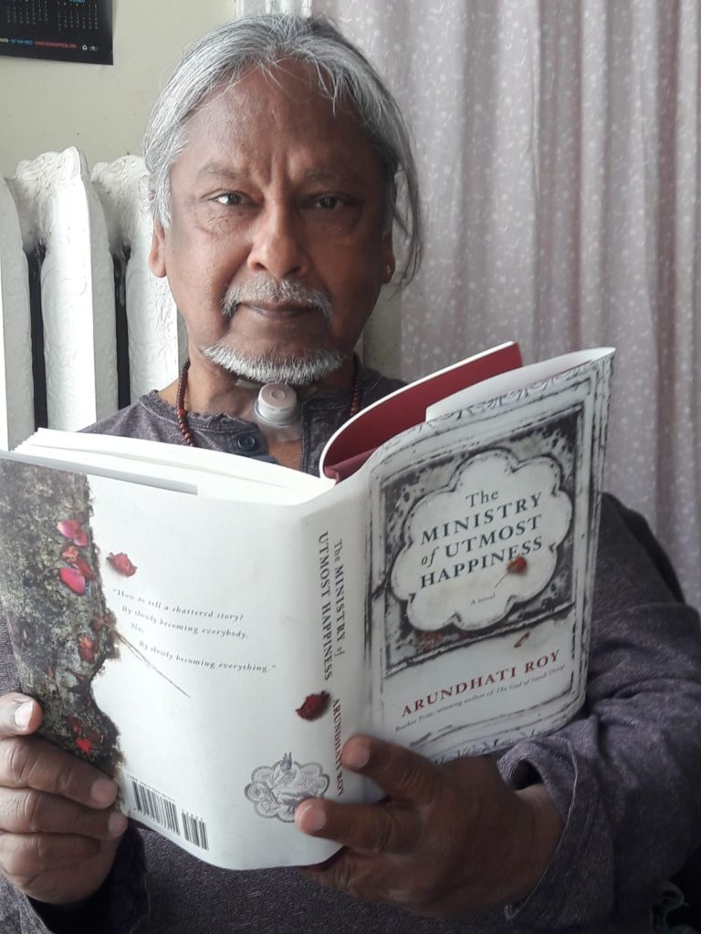 Ravi reading a book titled, The Ministry of Utmost Happiness, by Arundhati Roy