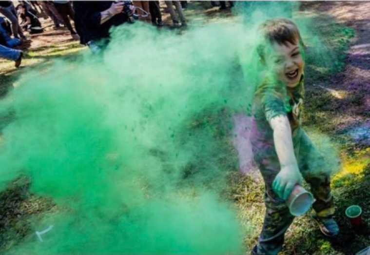 an image of a small child throwing powdered pigment at the camera and laughing;
